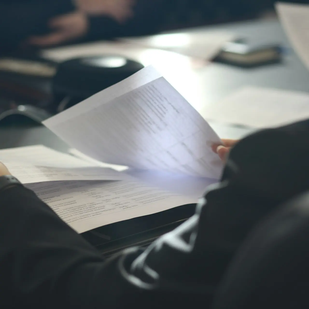 a woman sitting at a table reading a paper